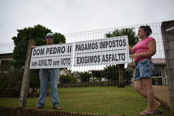 Mais uma comunidade usa placas para cobrar asfalto